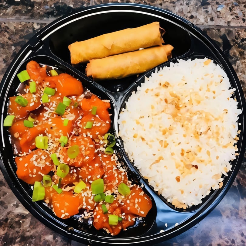 Emily's Filipino Food bento box with orange chicken, rice, and two crispy lumpia rolls.